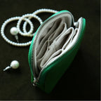 Green jewelry pouch with pearl earrings on a dark surface