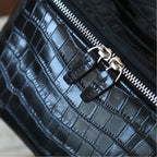 Close-up of a black leather makeup bag with a silver zipper and decorative silver zipper pulls.