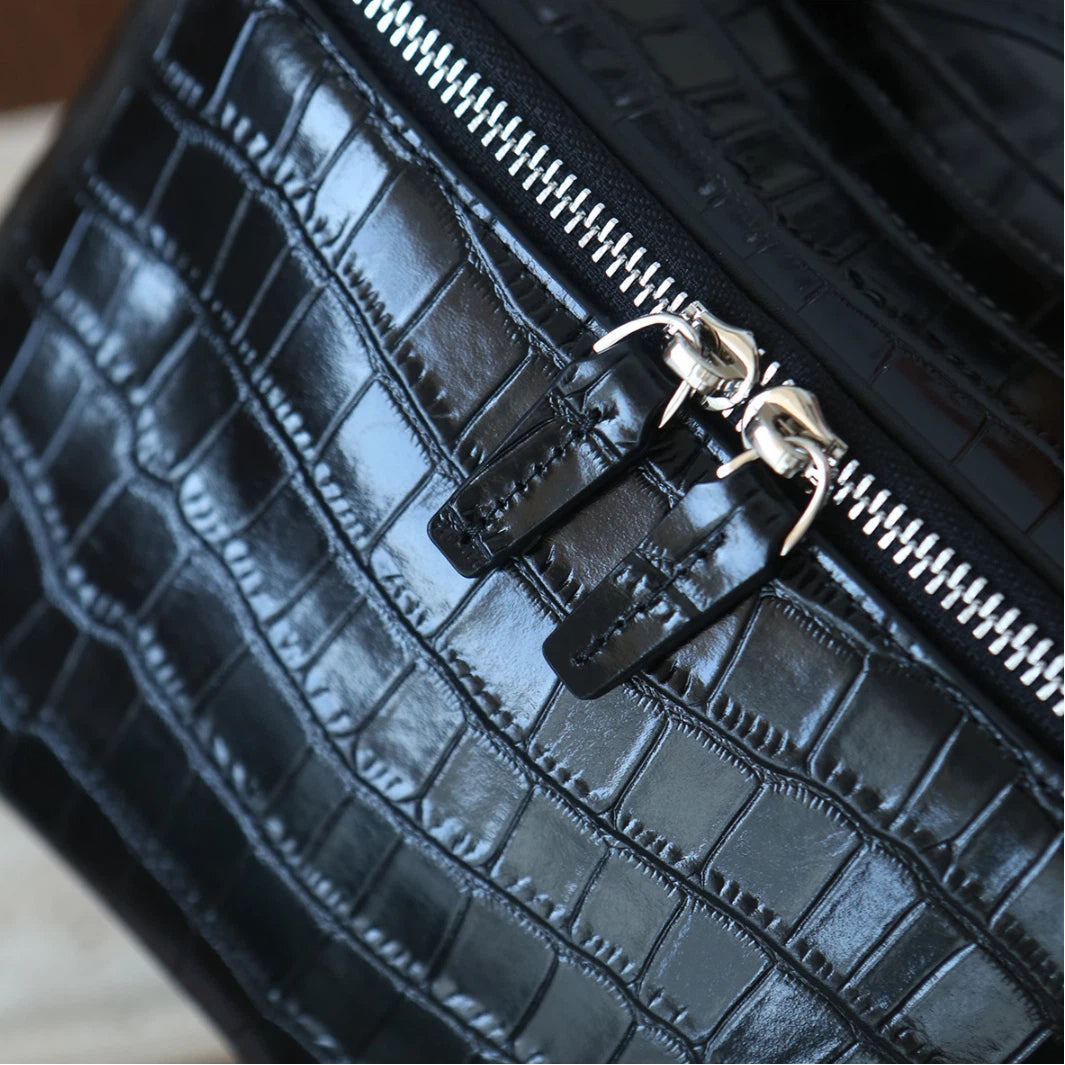Close-up of a black leather makeup bag with a silver zipper and decorative silver zipper pulls.