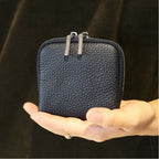 Black leather jewellery bag held in a hand against a dark background
