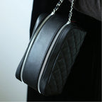 Black quilted makeup bag with a chain strap on a neutral background
