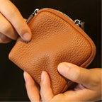 Brown leather jewellery bag held by a person against a dark background