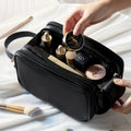 Black cosmetic bag with makeup items on a light background