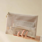 Hand holding a mesh pouch against a beige background