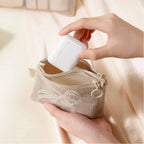 Person placing a Airpods into a small beige mesh pouch on a soft beige background