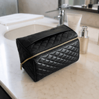 Black makeup bag on a bathroom counter with skincare products.